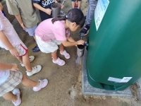 雨水タンクから水をくむ園児